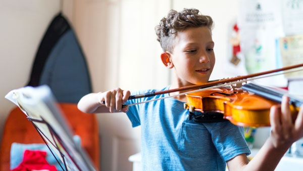 A boy practices playing the violin. 